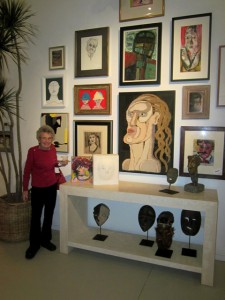 Peggy Gawecki stands in front of a wall of Expressionist portraits at Colin Fisher Studios